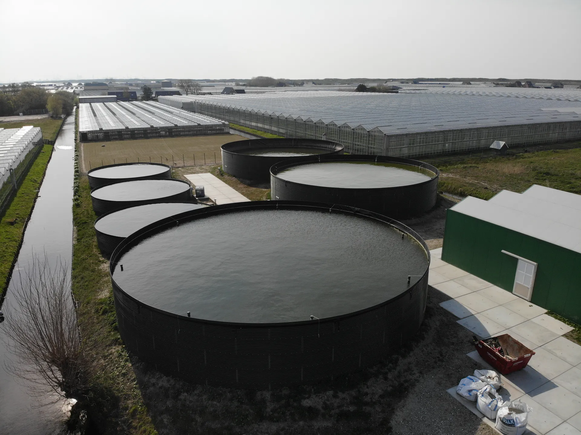 Hendic water storage tanks beside greenhouses
